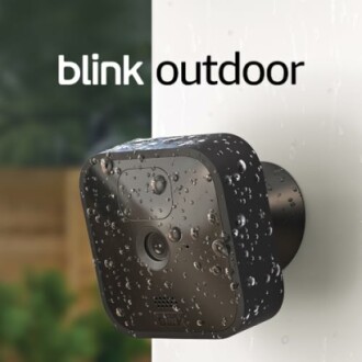 Blink outdoor camera mounted on wall with water droplets.