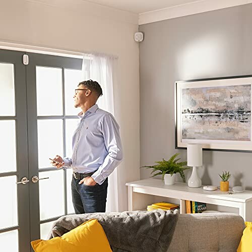 Man standing near glass doors in a bright room with modern decor.