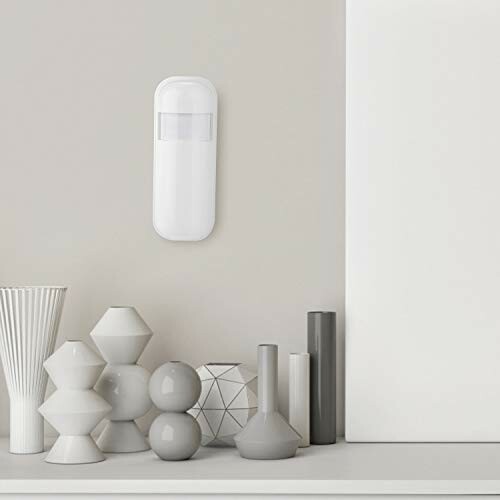 Contemporary vases and wall-mounted sensor on light wall